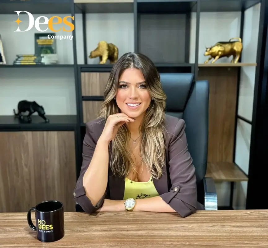 Nayara Jundi da Dees Company em seu escritório, com elementos que simbolizam o mercado financeiro ao fundo.